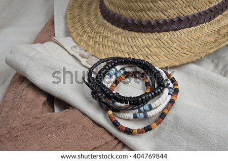 Straw hat, scarf, classic linen coat and bracelets. Stylish summertime outfit theme