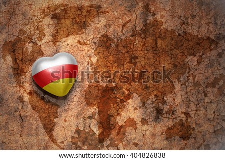 heart with national flag of south ossetia on a vintage world map crack paper background. concept