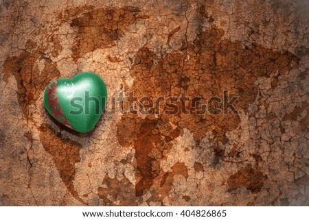heart with national flag of turkmenistan on a vintage world map crack paper background. concept