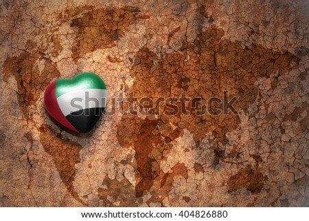 heart with national flag of united arab emirates on a vintage world map crack paper background. concept
