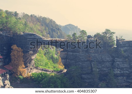 View of the mountain landscape and tourists under a rock in the shape of an arch. Toned