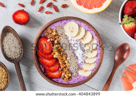 Smoothie bowl with chia seeds, muesli, strawberries, banana slices and coconut flakes Royalty-Free Stock Photo #404843899