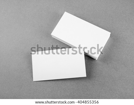 Photo of blank business cards on gray background. Mock-up for branding identity. For design presentations and portfolios. Top view. Grayscale image.