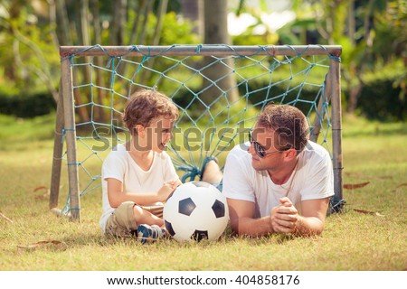 Father and son playing in the park  at the day time. Concept of friendly family. Picture made on the green meadow.