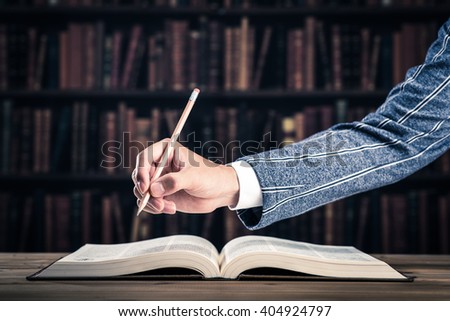 Hand holding a pen over a thick book