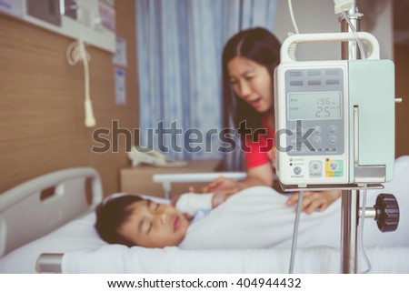 Illness asian child lying on sickbed with infusion pump intravenous IV drip. Mother take care her son. Shallow depth of field, IV machine in focus. Health care and medical concept. Vintage style.