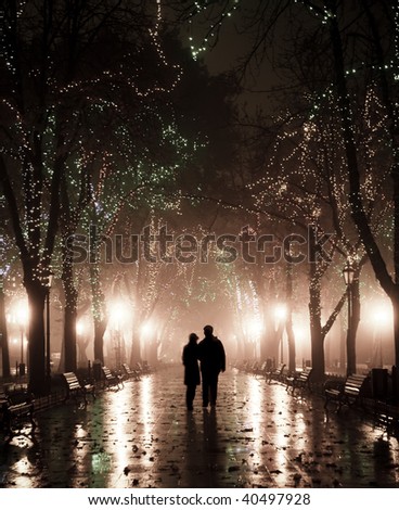 Couple walking at alley in night lights. Photo in vintage style.