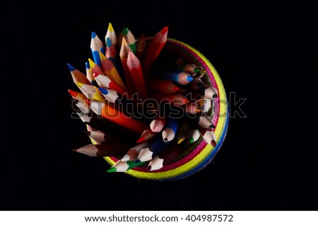 Colored Pencils in Rainbow Colored Jar, isolated on dark background, top view