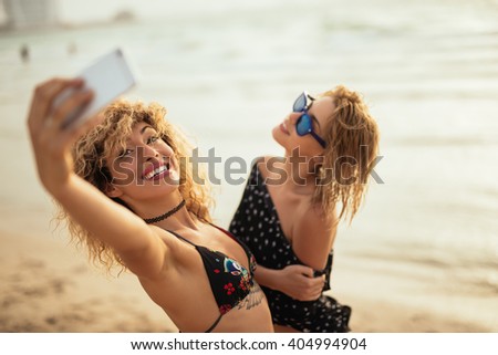 A beautiful young woman taking a selfie at the beach.