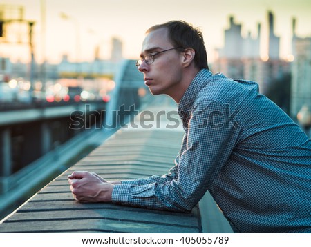 Skinny guy nerdy on the background of concrete walls at sunset