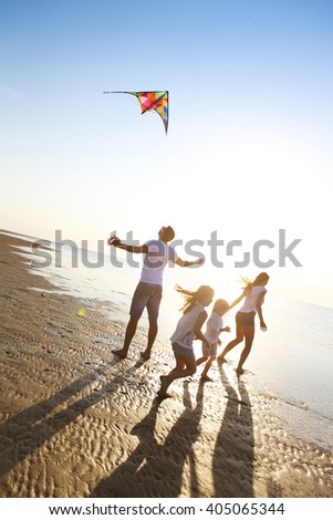 Happy young family with two kids with flying a kite on the beach