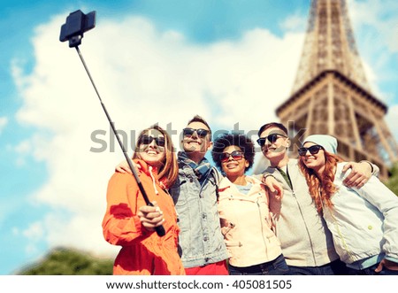 tourism, travel, people, leisure and technology concept - group of smiling teenage friends taking selfie with smartphone and monopod over paris eiffel tower background