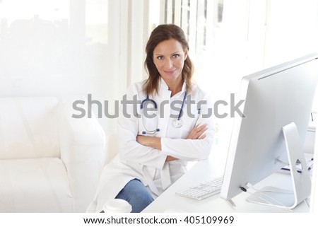 Portrait of middle aged female doctor sitting at private clinic in exam room.