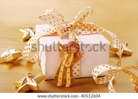 christmas present in white box with gold ribbon and wooden angel