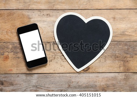 Smart phone on wooden table with heart background with copy space