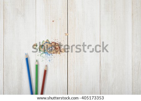 Green and blue colored pencils with its shavings on wooden plank