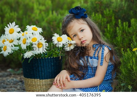 Portrait of a cute girl with big daisies in a basket. A large white chamomiles in a basket.