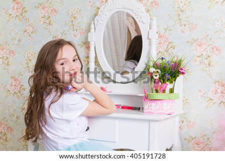 little caucasian girl sit  at dressing table (makeup table) near mirror