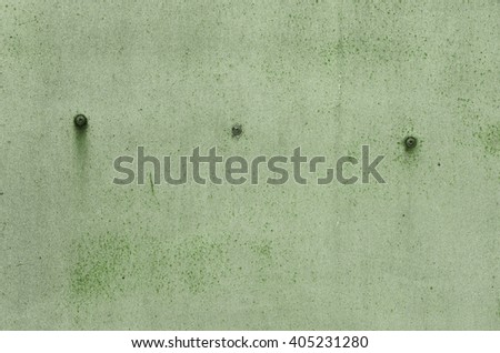 Green iron wall with old paint with streaks of rust and rusty screws. textural composition