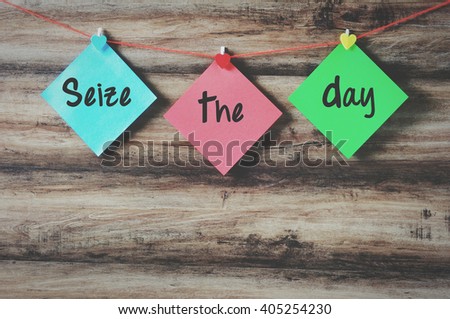 Seize the day on colorful paper with clothespin hanging on a string with wooden background, retro style.