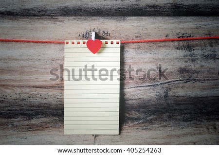 Recycled paper with clothespin hanging on a string with wooden background, retro style.