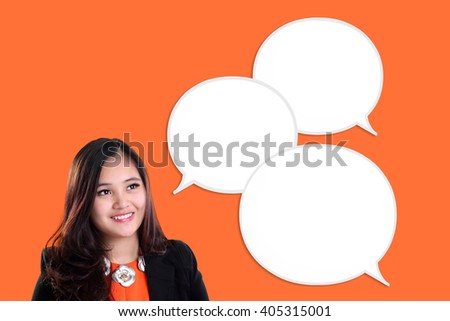 Modern Asian businesswoman smiling while looking at empty chat bubbles, on orange colored background
