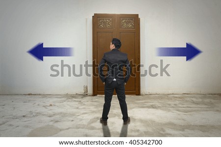 Businessman standing in doubt on the wood door,thinking the two different choices indicated by arrows pointing in opposite direction, business decision concept