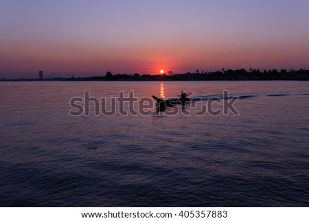 Color picture of people in a boat on a river at sunset.