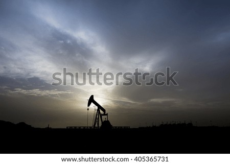 Cloudy Sunset and silhouette of crude oil pump unit in oilfield