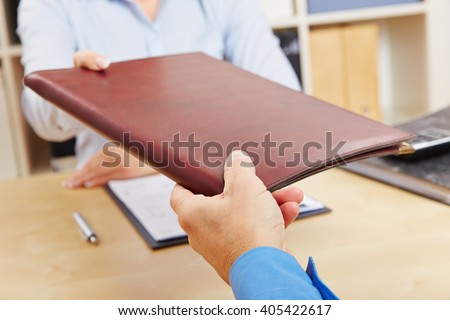 Hands of woman giving application portfolio to HR man in office Royalty-Free Stock Photo #405422617