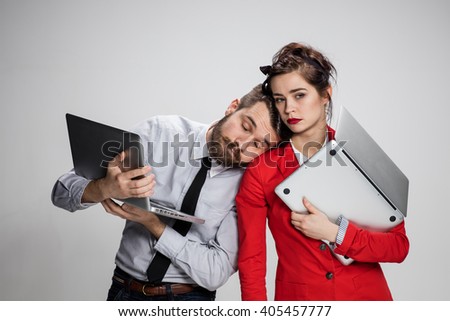 The young businessman and businesswoman with laptops  posing on gray background