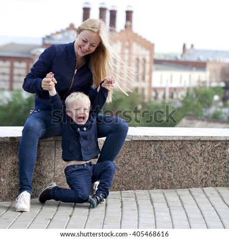 Beautiful young mother is holding her son in the summer park