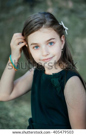 Spring fairy. Portrait of beautiful little girl with brownish blond hair and blue eyes standing outdoor on natural background.