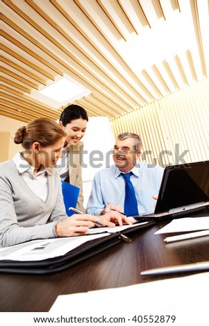 Photo of friendly business group sitting at the desk in the office and planning work