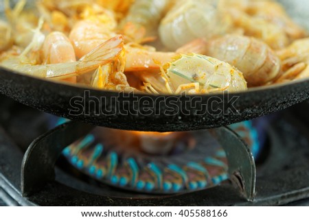 Silver Mantis Shrimp and Prawn cooked in the wok. Upper half picture showing shrimp and prawn inside the wok and below half picture showing the gas stove.In the middle of cooking process.