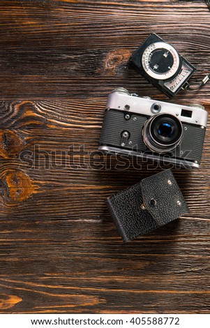 Old film camera, lenses and old exposure meter on a wooden background