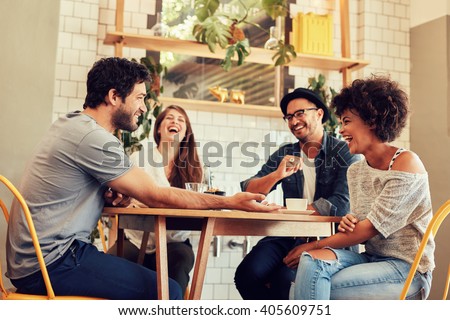 Young friends having a great time in restaurant. Group of young people sitting in a coffee shop and smiling. Royalty-Free Stock Photo #405609751
