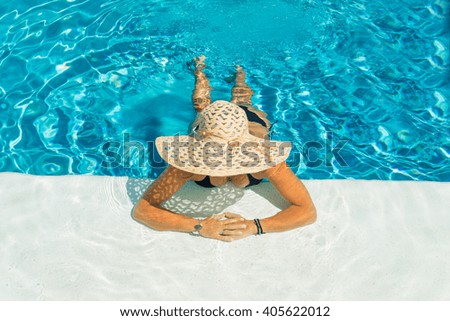 Pretty woman in a hat enjoying a swimming pool at the resort