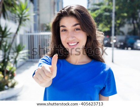 Caucasian woman in a blue shirt showing thumb up