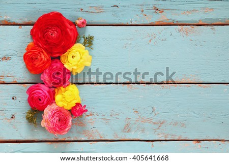 top view of colorful spring flowers on blue wooden background. vintage filtered
