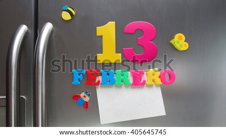 Febrero 13 (February 13 in Spanish language) calendar date made with plastic magnetic letters holding a note of graph paper on door refrigerator. Spanish version