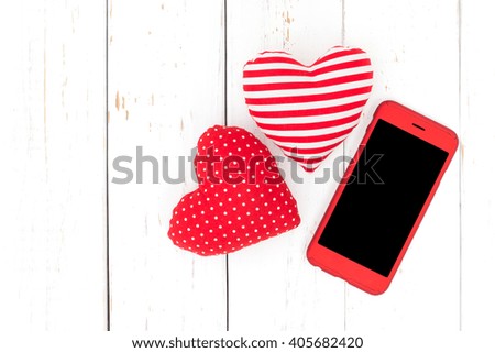 Smartphone with heart shapes on white wooden table. This picture has clipping path in screen section