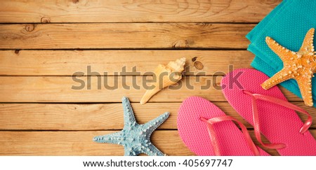 Flip flops with beach items on wooden deck background. View from above