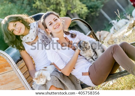outdoor portrait of young two happy women with cat on natural background on farm