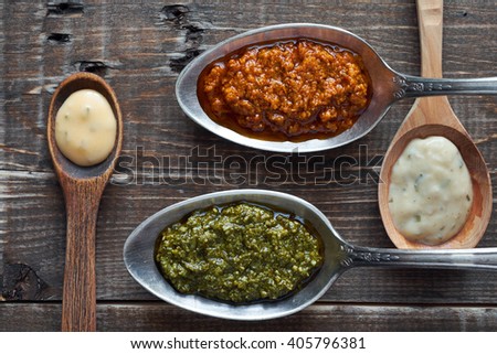 Different sauces in spoons on wooden table
