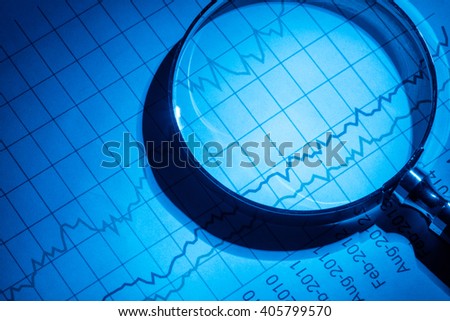 Business chart and magnifying glass, concept of analyzing.
