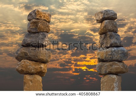 Large square granite blocks stack up to the balance with the sky and the sun as a backdrop.