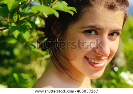 happy cute woman with flower in her hair smiling on background of green nature in mountains in summer