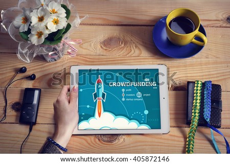 Laptop computer, tablet pc and Crowdfunding design concept on wooden office desk with copy space. Crowdfunding design concept background with rocket. 