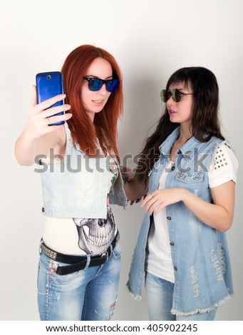 beauty hipster girls black and red in sunglasses, making selfie on a phone. teenagers grimace